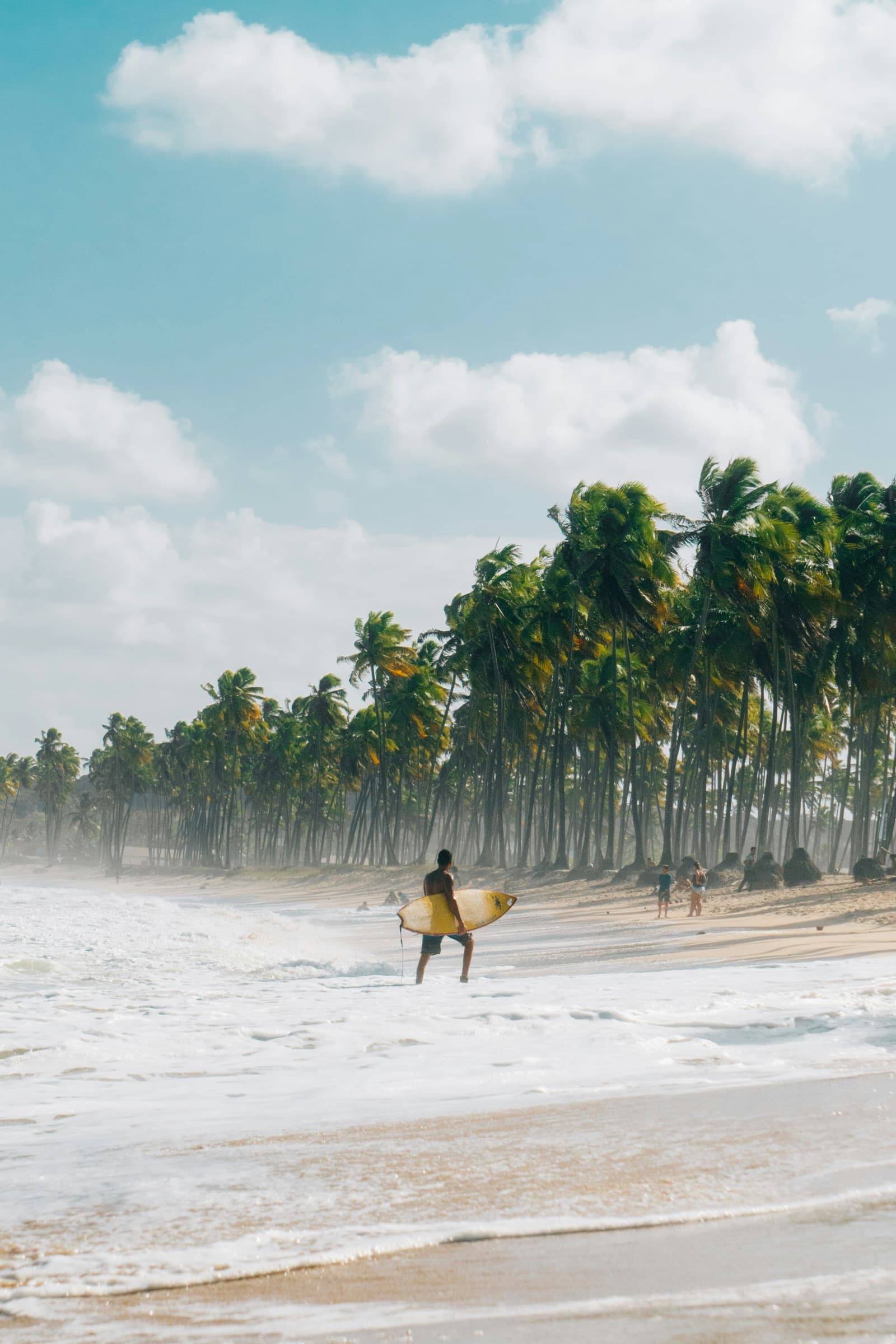 Surfista carregando prancha em praia nordestina